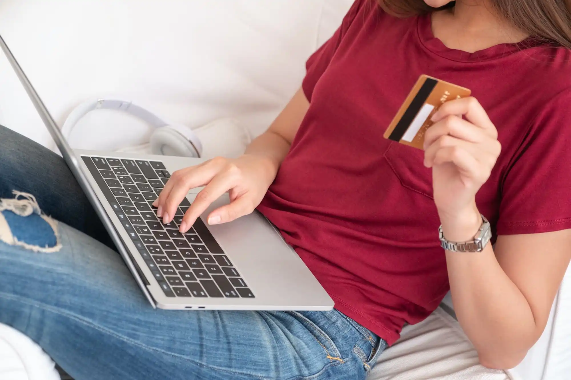 Close up woman holding credit card and use laptop shopping online on sofa