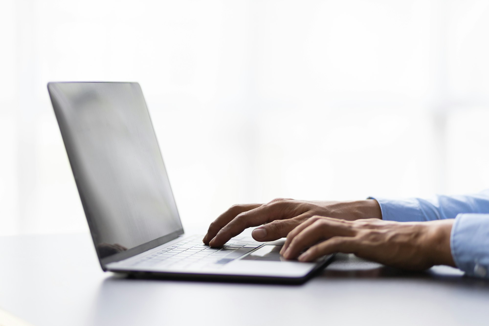 Male hand typing on laptop computer keyboard searching.