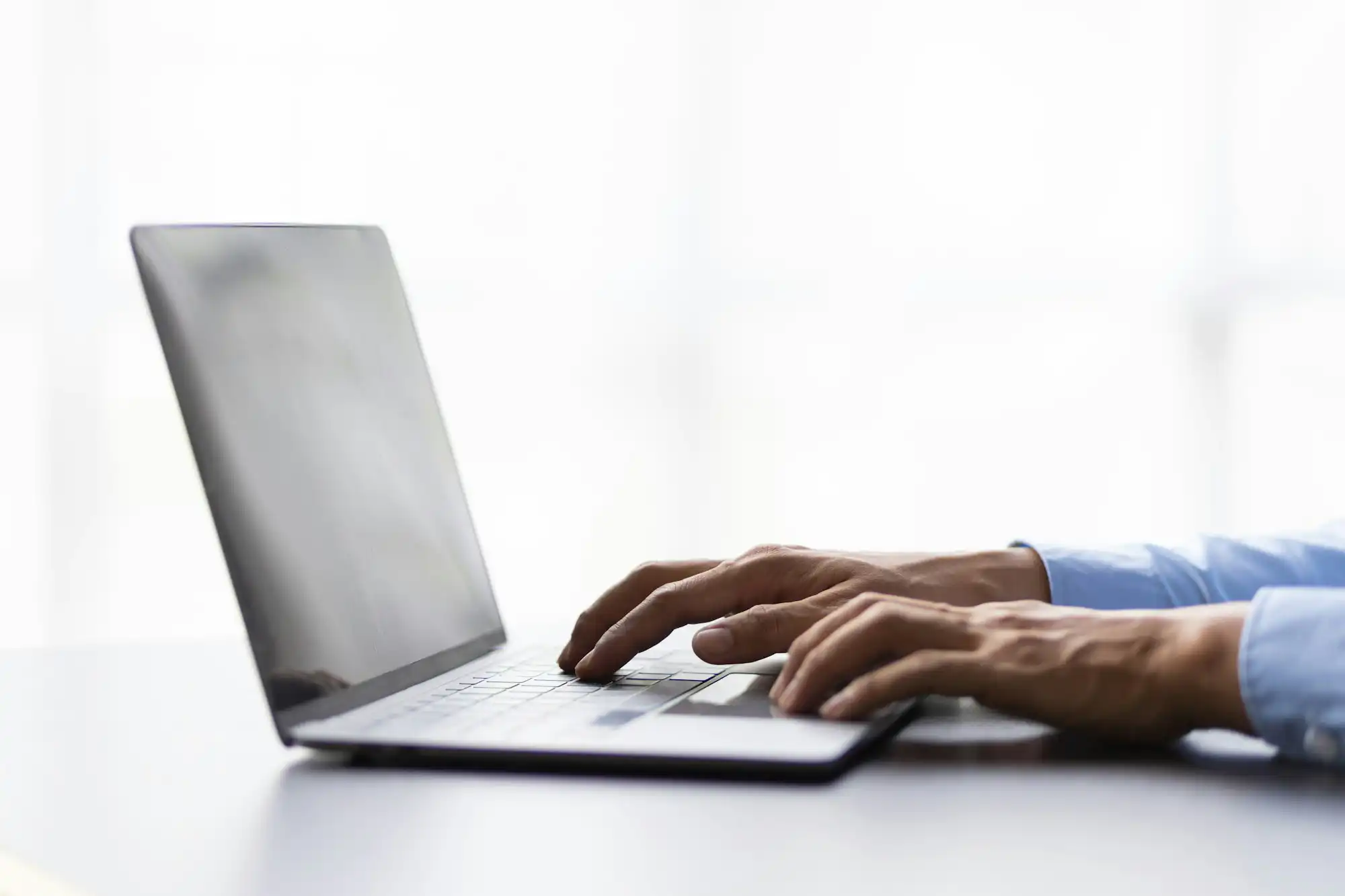 Male hand typing on laptop computer keyboard searching.