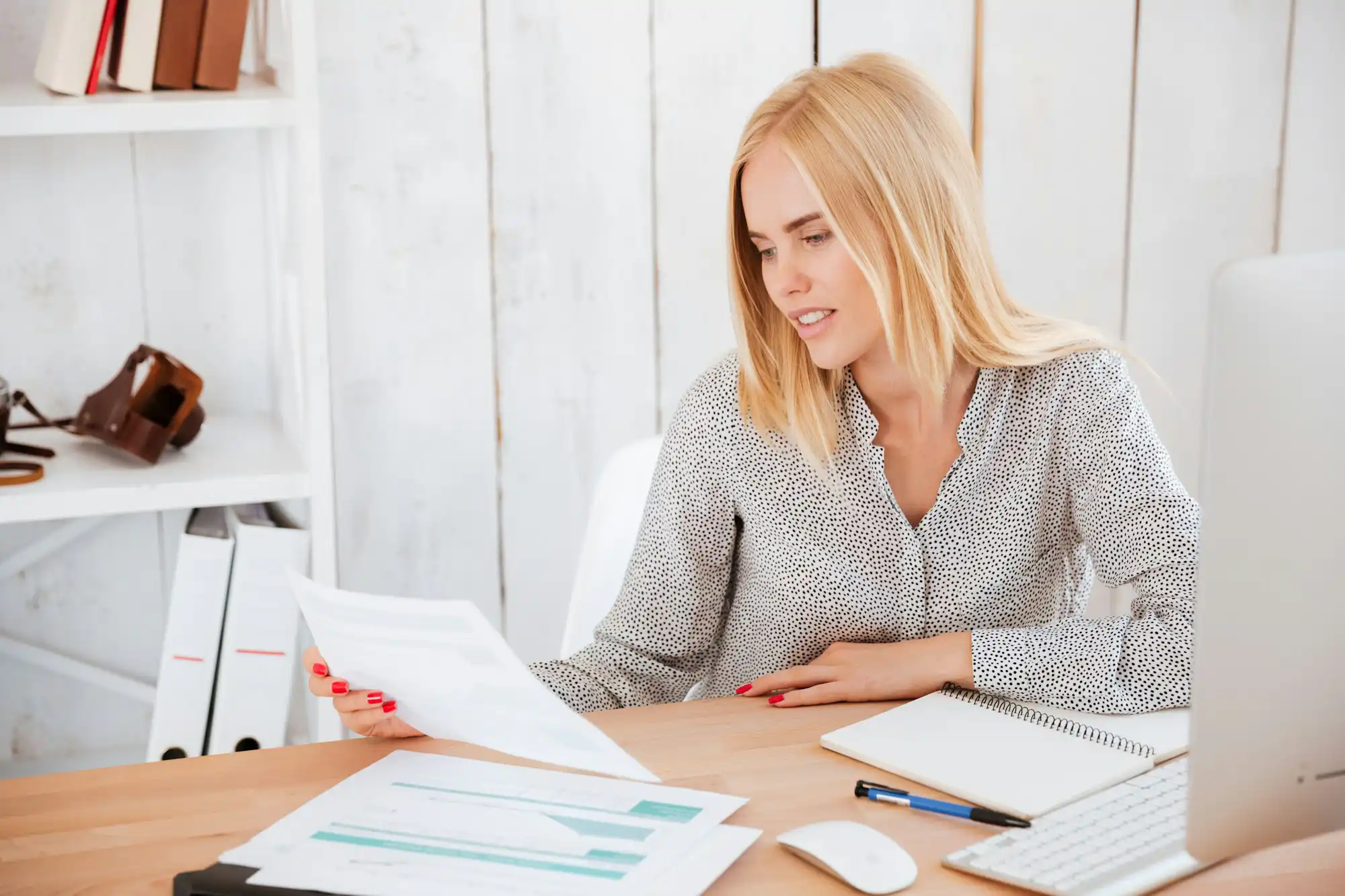 Businesswoman sitting at her working place with papers and pc